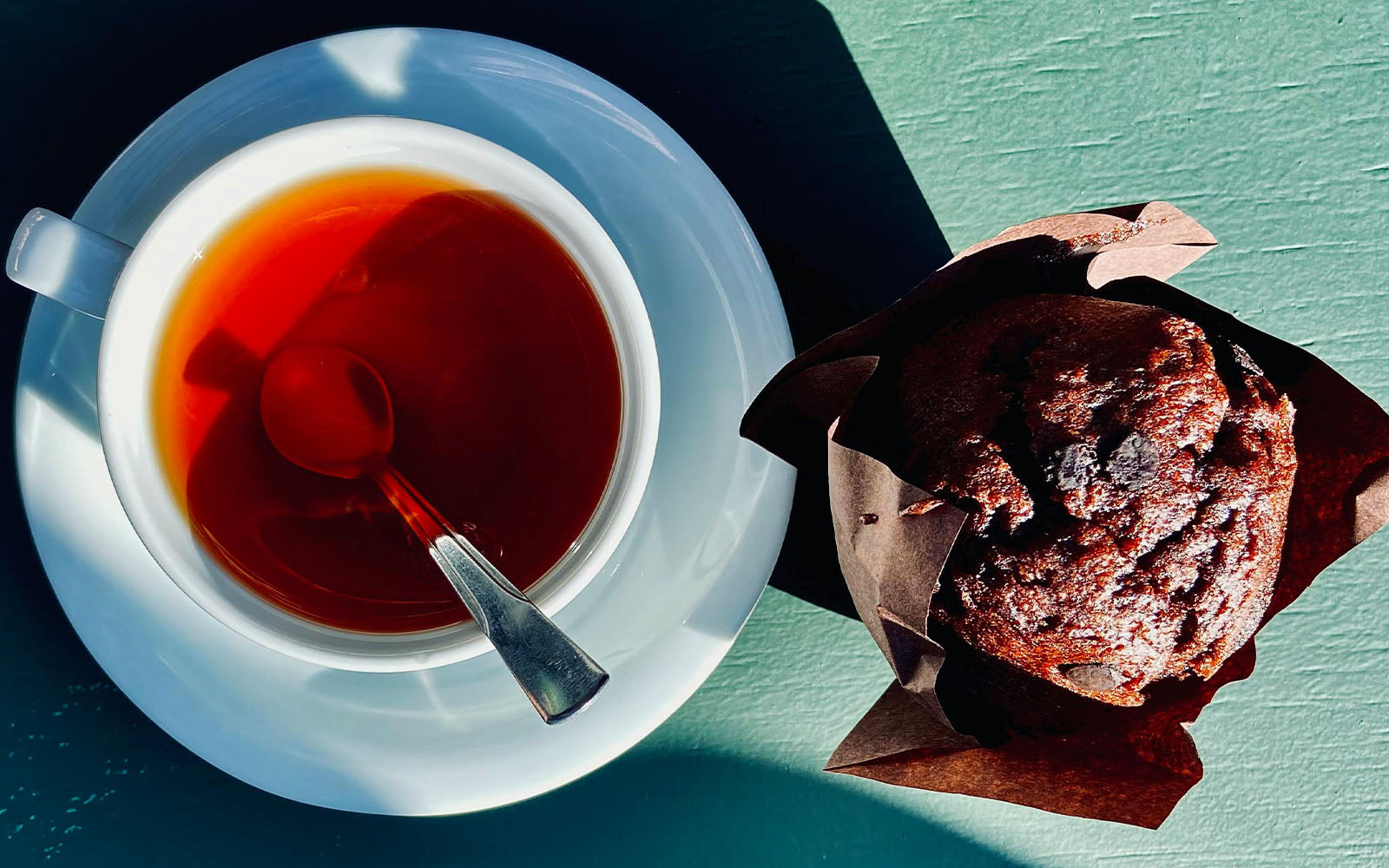 Teacup with english breakfast tea and a muffin on a blue table